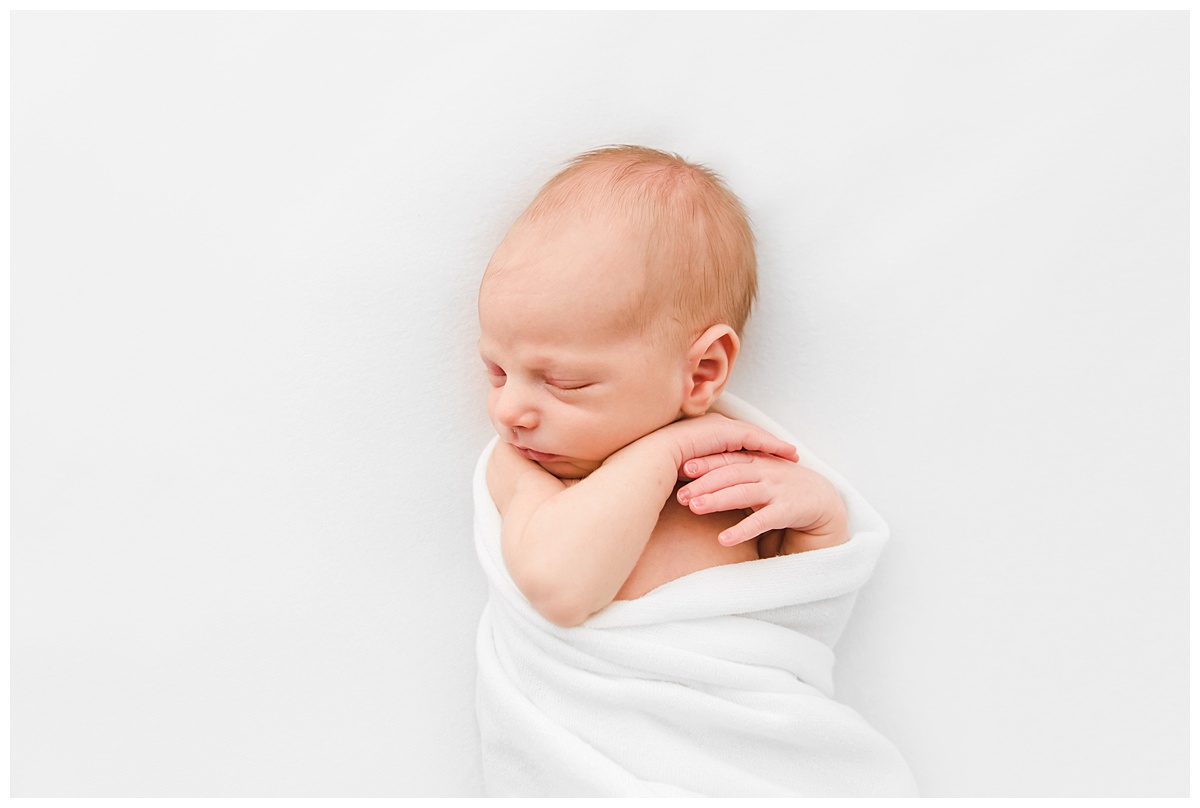 newborn baby wrapped in white blanket in boston photography studio