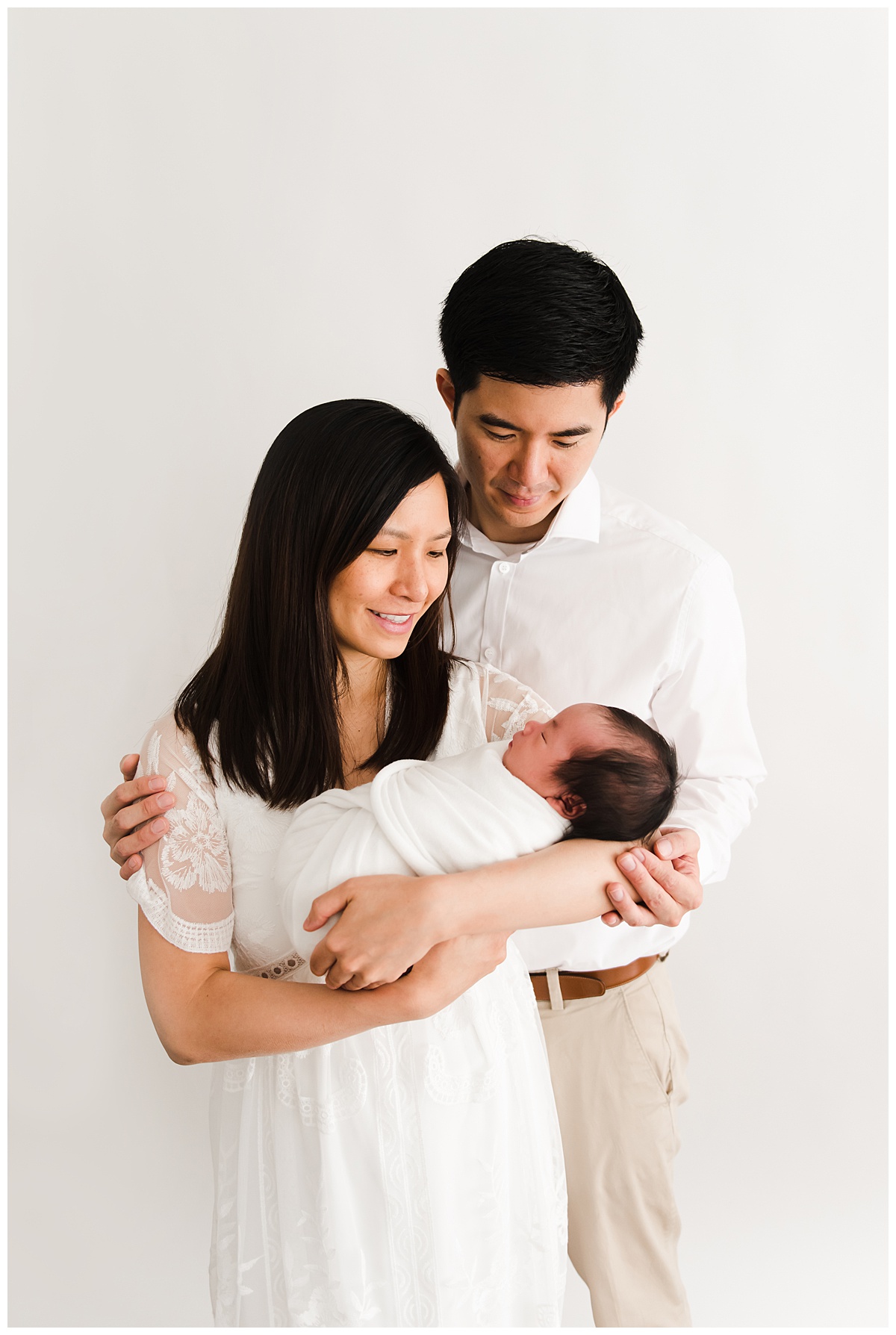 boston newborn photography session image of parents holding newborn in a white studio